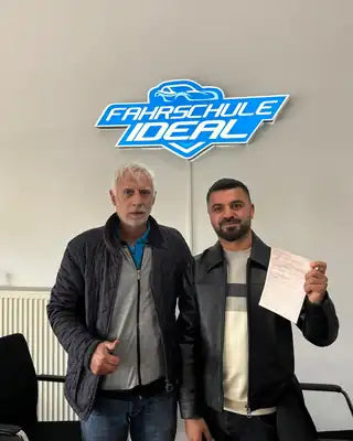 Fahrschüler nach bestandener Prüfung mit Fahrlehrer