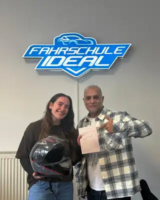 Fahrschülerin nach bestandener Motorradprüfung mit Fahrlehrer