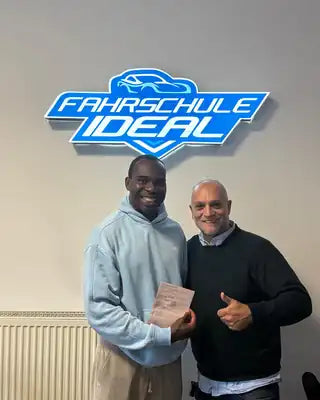 Fahrschüler nach bestandener Prüfung mit Fahrlehrer